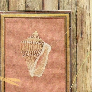 May include: Four framed cross-stitch embroidery pieces with nautical themes. The pieces feature a seagull, a seashell, a seahorse, and a crab. The frames are all different colors and styles.