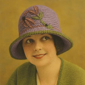 Może przedstawiać: Zdjęcie w stylu vintage kobiety w lawendowym kapeluszu cloche z kwiatowym haftem i zielonym wykończeniem. Ma również na sobie zielony kardigan. Obraz ma ciepłą paletę kolorów.