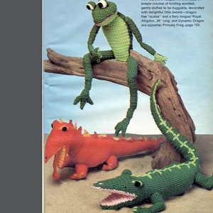 May include: A trio of crocheted stuffed animals: a green frog sitting on a branch, a red dragon, and a green alligator. The text on the page reads "trio of colorful creatures from storybook pages. All are made in simple crochet of knitting worsted, gently stuffed to be huggable, decorated with delightful little details-dragon has "scales" and a fiery tongue! Royal Alligator, 26" long, and Dynamic Dragon are opposite: Princely Frog, page 133."