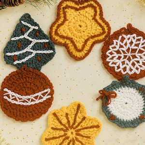 May include: A collection of seven handmade crochet Christmas ornaments in various shapes and colors. The ornaments include a Christmas tree, star, snowflake, and ball. The color palette includes shades of green, brown, white, and yellow. These ornaments are perfect for holiday decorating.