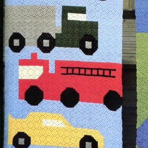 May include: A blue crocheted blanket with a traffic light, a red car, a green truck, a red fire truck, and a yellow car. Two children are standing behind the blanket.