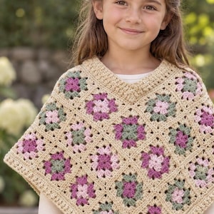 Puede incluir: Un poncho de ganchillo con un patrón de cuadrados granny en beige, rosa empolvado y verde salvia. La prenda tiene un escote en V y un dobladillo en punta, confeccionada con motivos cuadrados unidos con un borde beige sólido alrededor de cada uno.