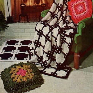 Puede incluir: Una manta de crochet blanca y negra con un patrón floral está drapeada sobre un sillón verde. Una almohada de crochet rosa con un diseño cuadrado está en la silla. Hay una alfombra de crochet más pequeña con un patrón floral similar en el suelo.