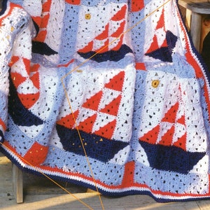 May include: A crocheted baby blanket with a nautical theme. The blanket is made of blue, white and red yarn and features a sailboat design.