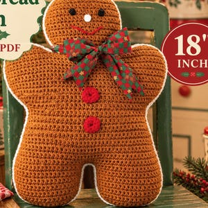 May include: A brown crochet gingerbread man plush toy with a white border, black eyes, a white nose, a red stitched mouth, and two red buttons. A green and red checkered bow is tied around its neck. The text reads Vintage Crochet Gingerbread Man PATTERN PDF and 18 INCH.