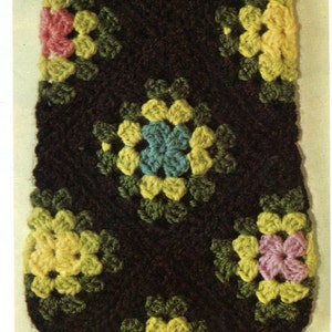May include: A brown crocheted fabric with a repeating pattern of colorful flowers. The flowers are yellow, pink, green, and blue.