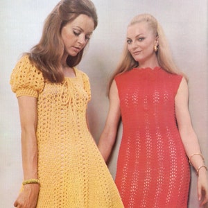 May include: Two women wearing crocheted dresses. The woman on the left is wearing a yellow dress with short sleeves and a scoop neck. The woman on the right is wearing a red sleeveless dress with a round neck.