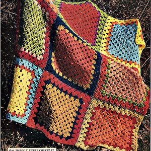 May include: A colorful crocheted blanket made of granny squares in red, orange, yellow, green, blue, and purple. The blanket is made of worsted weight yarn and is arranged in a three by three pattern.