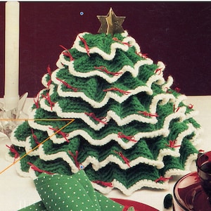 May include: A crocheted Christmas tree table centerpiece in green and white with red bows. The tree is decorated with a gold star on top.