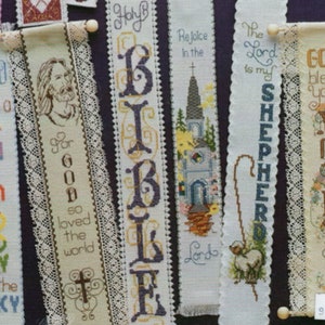 Peut inclure: Une collection de huit marque-pages brod&eacute;s sur des th&egrave;mes religieux. Les marque-pages sont en tissu blanc avec des broderies color&eacute;es. Les th&egrave;mes incluent "Dieu a mis un arc-en-ciel dans le ciel", "Car Dieu a tant aim&eacute; le monde", "Sainte Bible", "R&eacute;jouissez-vous dans le Seigneur", "Le Seigneur est mon berger", "Que Dieu vous b&eacute;nisse, M&egrave;re", et deux autres avec un texte peu clair.