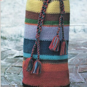 K&ouml;nnte beinhalten: Eine bunte gestreifte geh&auml;kelte Kordeltasche mit schwarzen, gelben, braunen, gr&uuml;nen, violetten, blauen und roten Streifen. Die Tasche hat einen schwarzen Kordelzug mit Quasten.