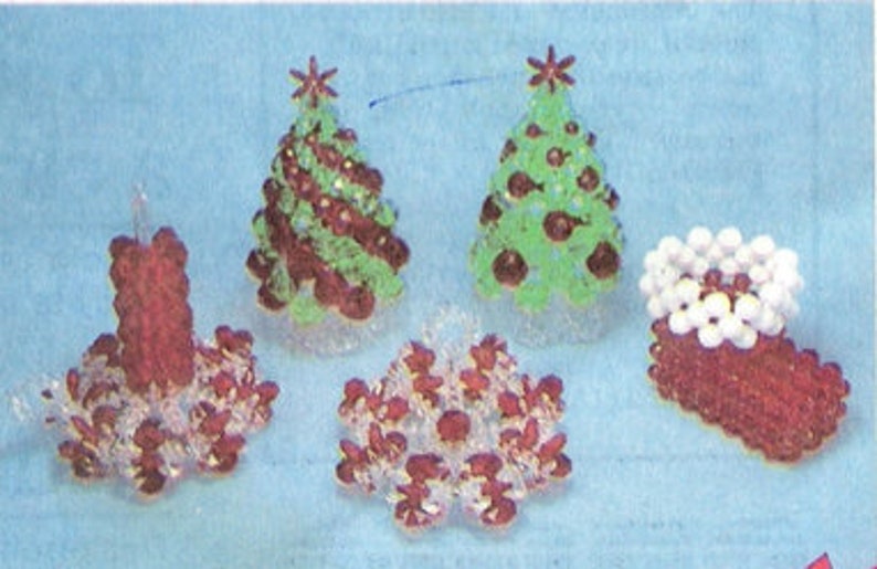 Op de afbeelding: Een verzameling handgemaakte kerstversieringen. De ornamenten omvatten een rood-witte kralen kandelaar, twee kralen kerstbomen, een rood-witte kralen sneeuwvlok en een rood-witte kralen kous.