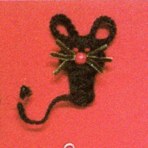 May include: A black crocheted mouse with a red button nose and green yarn whiskers. The mouse has a long, curled tail.