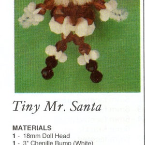 Op de afbeelding: Een handgemaakte Tiny Mr. Santa figuur, gemaakt van een poppenhoofd, chenille, draad, kralen en sterren. De figuur heeft een witte baard en hoed, een rode jas en zwarte en witte accenten. De tekst "Tiny Mr. Santa" is zichtbaar.