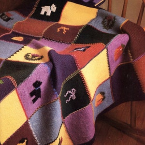 May include: A multi-coloured knitted baby blanket with a patchwork design featuring various animal and fruit motifs. The blanket is made of soft yarn and has a fringed edge.