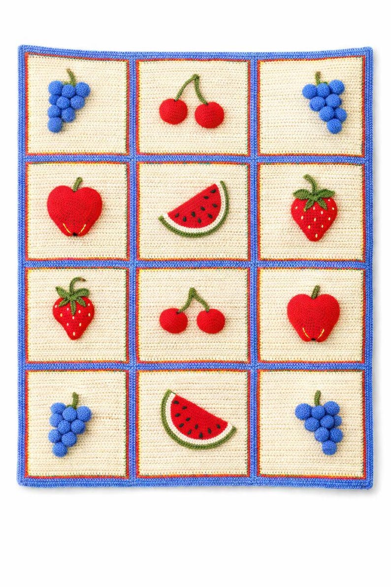 May include: A rectangular crochet blanket featuring a grid of twelve cream-colored squares bordered by blue yarn. Each square displays a three-dimensional crocheted fruit motif, including red cherries, blue grapes, red strawberries, red apples, and watermelon slices.
