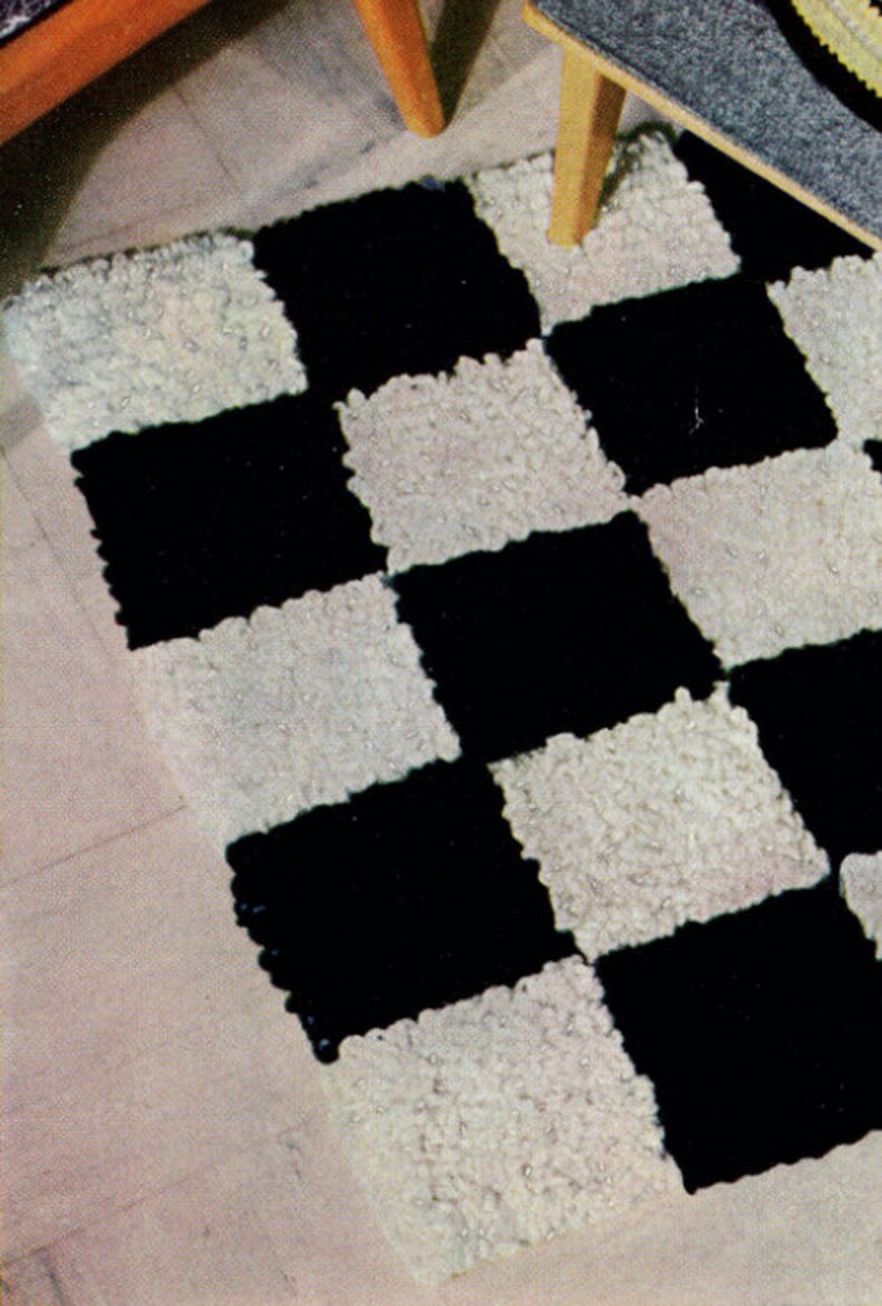 May include: A black and white checkerboard rug with a textured, looped pile. The rug is rectangular and features alternating black and white squares. The rug is placed on a light-colored wooden floor, with the legs of a chair visible.