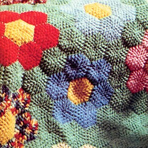 May include: A close-up of a colorful crocheted rug with a variety of flower designs in shades of red, blue, yellow, white, and green.