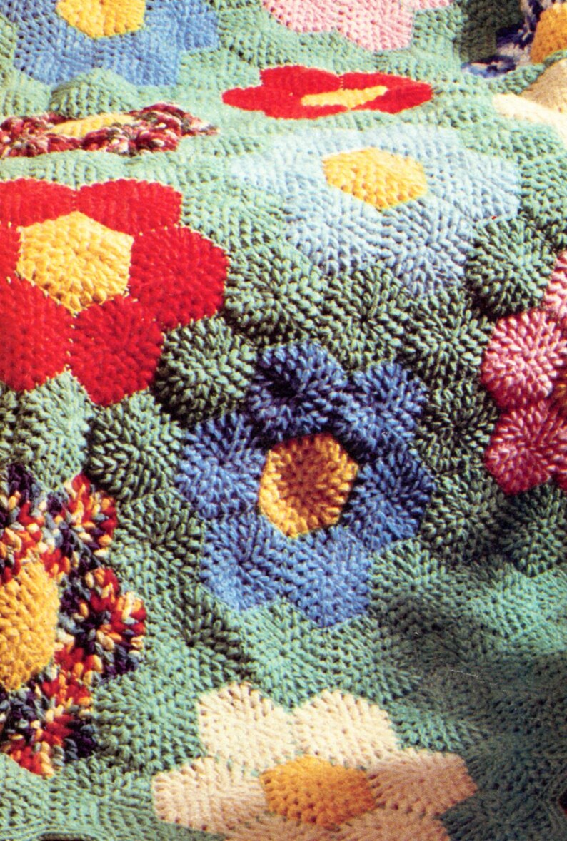 May include: A close-up of a colorful crocheted rug with a variety of flower designs in shades of red, blue, yellow, white, and green.