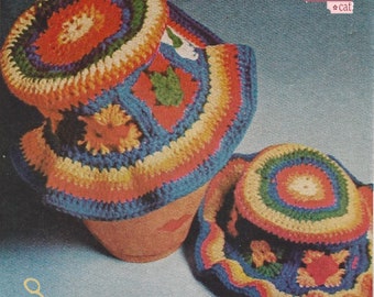 May include: Two crocheted hats in a rainbow color pattern with flower designs. The hats are made with blue, green, yellow, orange, and red yarn.