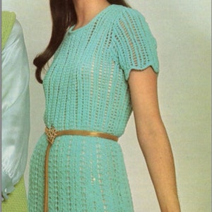 May include: A woman wearing a turquoise crochet dress with a brown belt and a patterned headscarf.