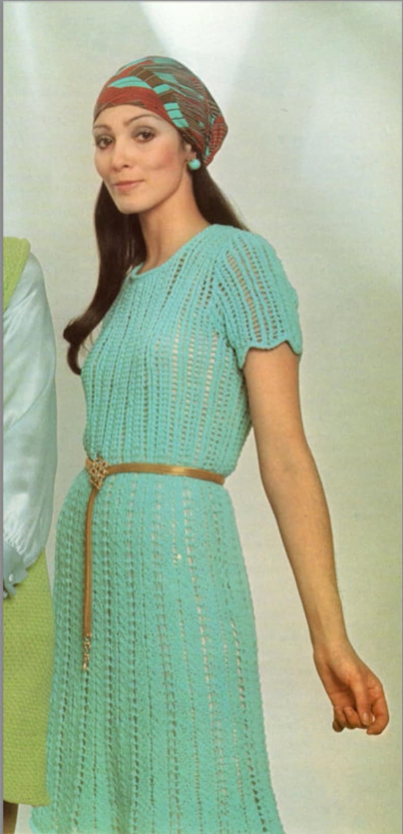 May include: A woman wearing a turquoise crochet dress with a brown belt and a patterned headscarf.