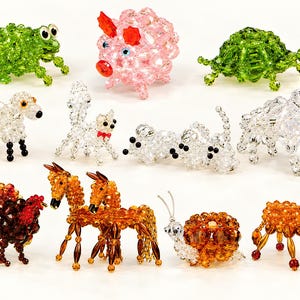 Puede incluir: Una colección de doce pequeñas figuras de animales hechas de cuentas de cristal facetado. El conjunto incluye una rana verde, un cerdo rosa, una tortuga verde, una oveja, un gato, un perro, un toro, un pavo, dos caballos, un caracol y un burro.