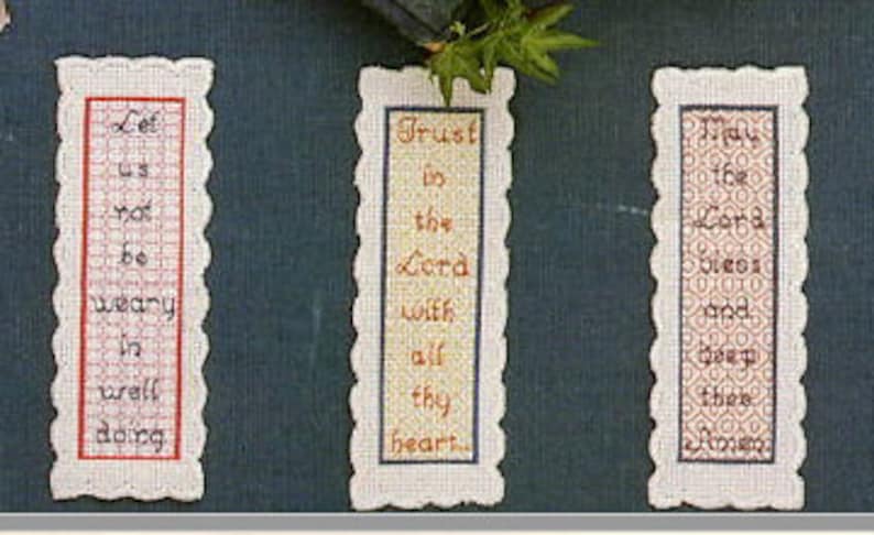 May include: Three rectangular bookmarks with scalloped edges and embroidered text. The first bookmark is red with the text "Let us not be weary in well doing". The second bookmark is yellow with the text "Trust in the Lord with all thy heart". The third bookmark is brown with the text "Do the Lord's work and keep thee close".