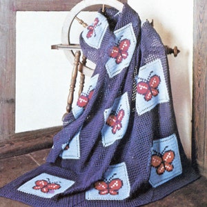 May include: A crocheted blanket with a purple background and blue squares featuring red butterfly designs.
