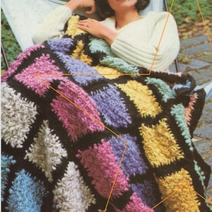 Könnte beinhalten: Eine bunte Häkeldecke mit einem Rautenmuster in den Farben Rosa, Blau, Gelb und Weiß. Die Decke ist aus dickem Garn gefertigt und hat eine strukturierte Optik.