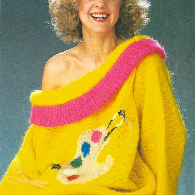 May include: A yellow fuzzy sweater with a pink trim around the neckline. The sweater has a colorful paint palette design on the front.