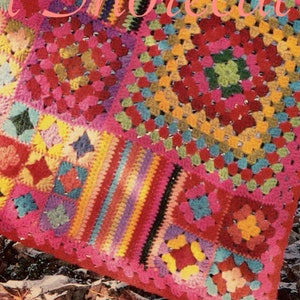 May include: A colourful crocheted blanket featuring a variety of squares in different colours and patterns, including pink, red, yellow, green, blue, and purple.