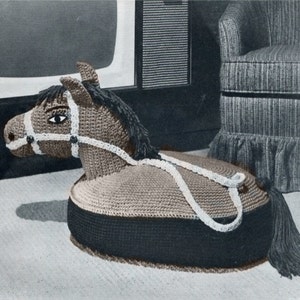 Peut inclure: Un repose-pieds en forme de cheval crocheté avec un corps brun, des sabots noirs et une bride blanche. Le repose-pieds est posé sur un tapis gris clair.
