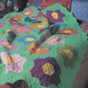 May include: A green crochet blanket with a multi-colored flower pattern. The blanket is made with different shades of pink, purple, blue, yellow, and orange.