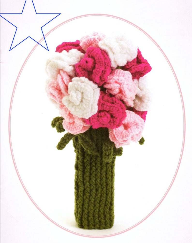 May include: A crocheted bouquet of pink, white, and light pink flowers in a green crocheted vase.