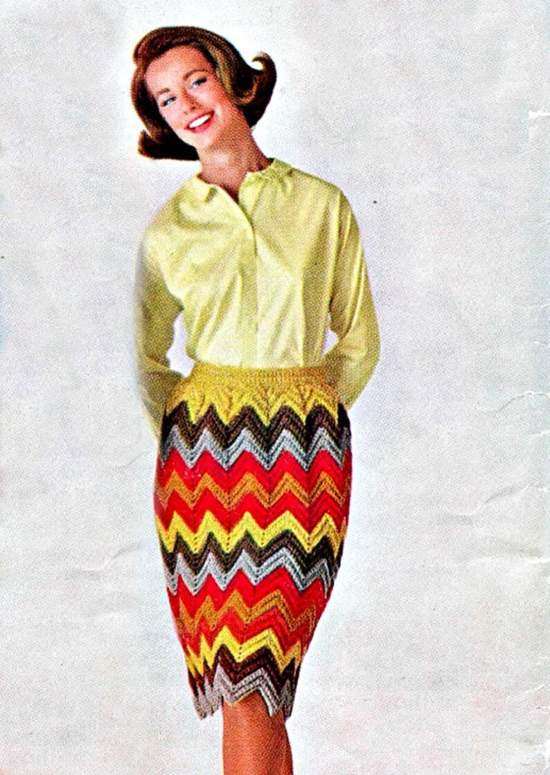 Peut inclure: Une femme porte une chemise jaune &agrave; manches longues et une jupe &agrave; motifs chevrons multicolores. La jupe pr&eacute;sente un motif en zigzag rouge, jaune, marron et argent&eacute;. La jupe arrive au genou.