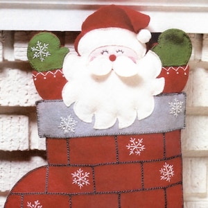 May include: A red and white felt stocking with a Santa Claus face peeking out of the top. The stocking has a gray felt chimney with white snowflake embroidery. The stocking is hanging on a white brick wall.