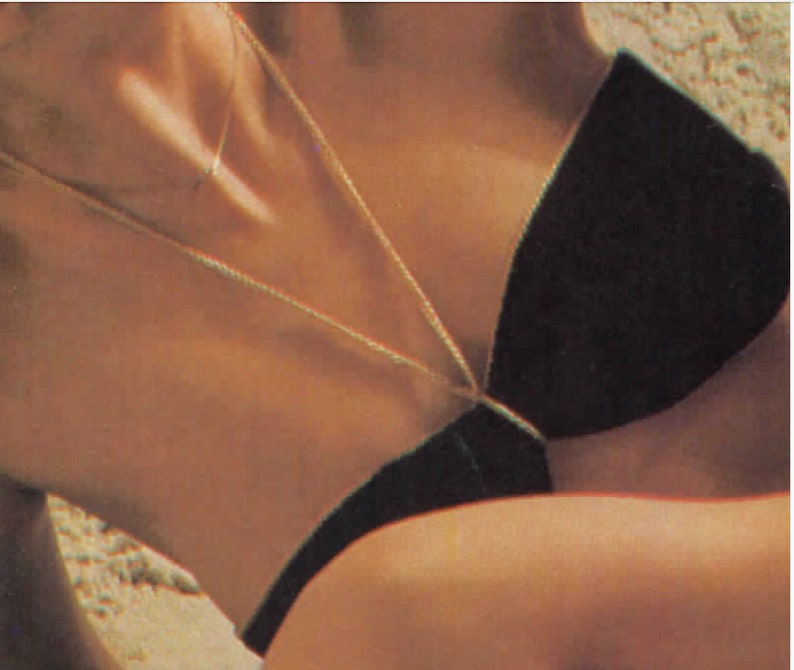 Puede incluir: Primer plano del pecho de una mujer que lleva un top de bikini negro con un collar de cadena dorada.