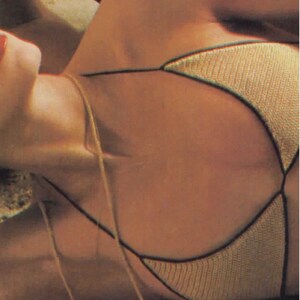 Puede incluir: Primer plano de la parte superior de un bikini de ganchillo que lleva una mujer. La parte superior es de color marr&oacute;n claro con un ribete marr&oacute;n oscuro. La parte superior est&aacute; atada al cuello y a la espalda.