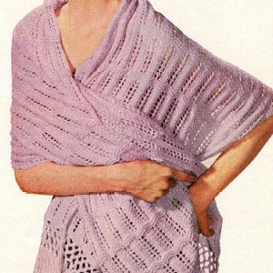 May include: A woman wearing a light purple crocheted shawl with fringe. The shawl is draped over her shoulders and tied at the waist.