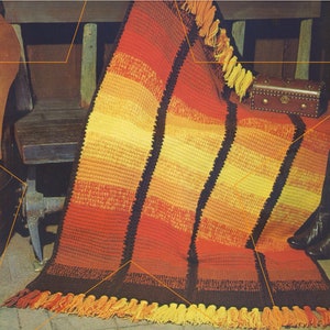 May include: A crocheted throw blanket with a striped pattern in shades of orange, yellow, and brown. The blanket has fringe along the bottom edge.