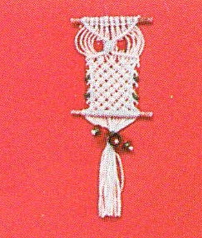 May include: White macrame owl wall hanging with a tassel. The owl has a diamond pattern on its body and a simple design for its eyes.