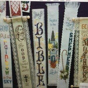 Peut inclure: Une collection de marque-pages en point de croix sur des th&egrave;mes religieux. Les marque-pages pr&eacute;sentent une vari&eacute;t&eacute; de motifs, notamment un arc-en-ciel, une croix, une &eacute;glise, un berger et le mot "BIBLE".