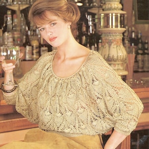 Op de afbeelding: Een beige gehaakt topje met een losse, vloeiende pasvorm en een ronde hals. Het topje heeft een delicaat, kantpatroon.
