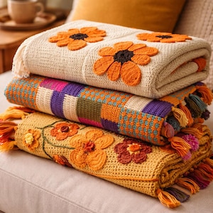 May include: A stack of three folded crochet blankets. The top blanket is cream-colored with orange flower appliqués. The middle blanket has a patchwork design in various colors. The bottom blanket is yellow with orange and brown flower appliqués and fringe.