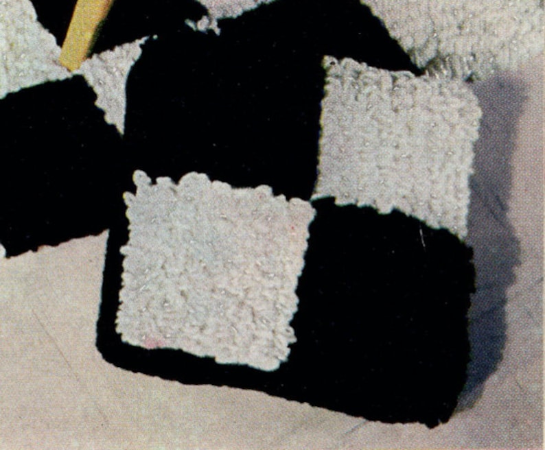 May include: Close-up of a black and white checkerboard pattern. The squares are textured, with the white squares appearing to have a fuzzy, raised surface. The black squares are smooth. The overall design is geometric and graphic.