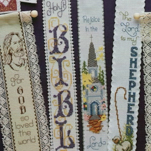 Peut inclure: Une collection de huit marque-pages brod&eacute;s sur des th&egrave;mes religieux. Les marque-pages sont blancs avec des broderies color&eacute;es et certains ont une bordure en dentelle. Le texte sur les marque-pages comprend "Dieu a mis un arc-en-ciel", "Car Dieu a tant aim&eacute; le monde", "Sainte Bible", "R&eacute;jouissez-vous dans le Seigneur", "Le Seigneur est mon berger", "Que Dieu vous b&eacute;nisse, M&egrave;re", et "Le Seigneur est mon berger".