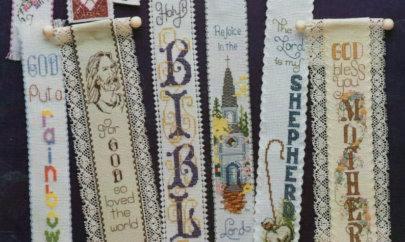Peut inclure: Une collection de huit marque-pages brod&eacute;s sur des th&egrave;mes religieux. Les marque-pages sont blancs avec des broderies color&eacute;es et certains ont une bordure en dentelle. Le texte sur les marque-pages comprend "Dieu a mis un arc-en-ciel", "Car Dieu a tant aim&eacute; le monde", "Sainte Bible", "R&eacute;jouissez-vous dans le Seigneur", "Le Seigneur est mon berger", "Que Dieu vous b&eacute;nisse, M&egrave;re", et "Le Seigneur est mon berger".