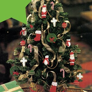 May include: A small artificial Christmas tree decorated with crocheted ornaments, including a snowman, Santa Claus, a stocking, a wreath, and candy canes.