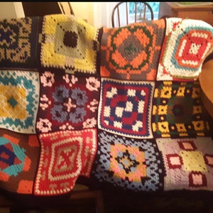 May include: A colorful crocheted blanket made of squares with different patterns and colors, including red, blue, yellow, green, and brown.